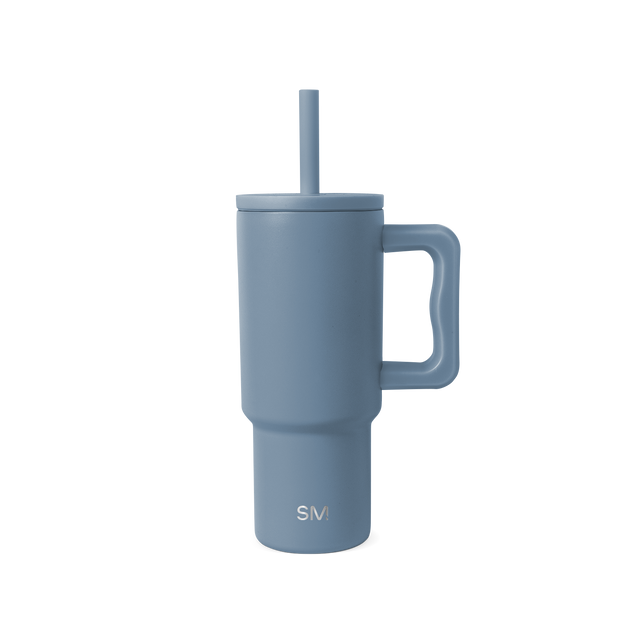 Slate blue dusty tumbler with white interior against neutral off-white background Slate blue dusty tumbler with white interior against neutral off-white background