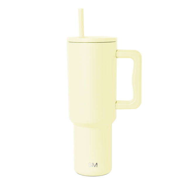 Pale butter yellow 40-ounce Simple Modern insulated tumbler with handle, flat lid, straw opening, and matching yellow straw on white background. Pale butter yellow 40-ounce Simple Modern insulated tumbler with handle, flat lid, straw opening, and matching yellow straw on white background.