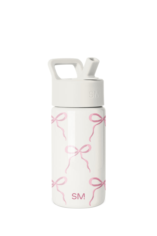 White Simple Modern water bottle with pink bow pattern, wide-mouth design, white screw-on cap with handle and straw opening, SM logo on lid and lower body, studio product shot on white background. White Simple Modern water bottle with pink bow pattern, wide-mouth design, white screw-on cap with handle and straw opening, SM logo on lid and lower body, studio product shot on white background.