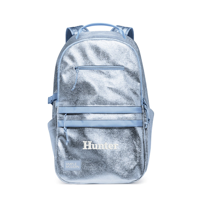 Light blue metallic backpack with dual padded straps, top handle, and front zippered pocket. Features 