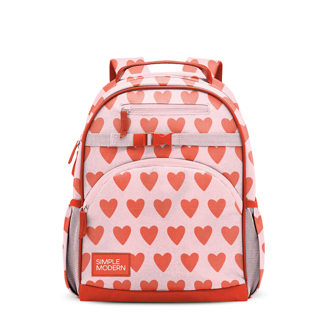 Light pink children's backpack with coral-red heart pattern, padded handles, cushioned straps, front zippered pocket, side mesh pockets, and coral-red bottom panel. Simple Modern branded label visible.