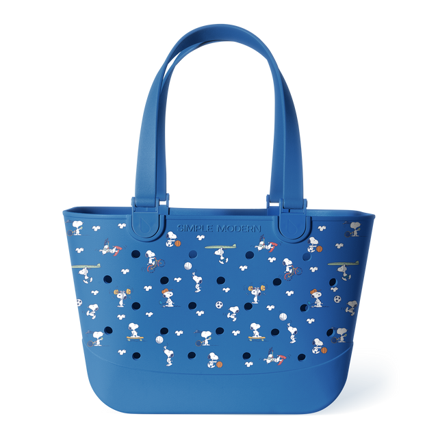 Blue Peanuts tote bag with dual handles, perforated front panel, and character print featuring Snoopy playing sports and activities in white and orange. Simple Modern branding on solid blue base.