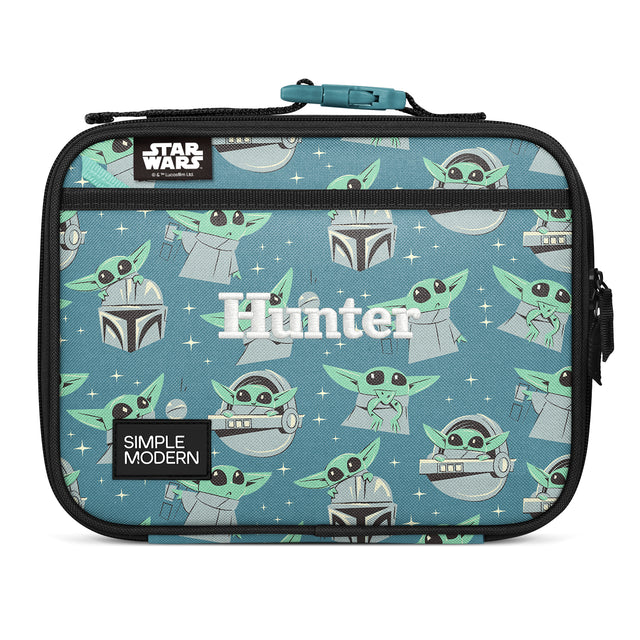 Dusty blue-teal insulated lunch bag with Grogu and Mandalorian helmet pattern, black mesh pocket with teal zipper, webbing handle, labeled 