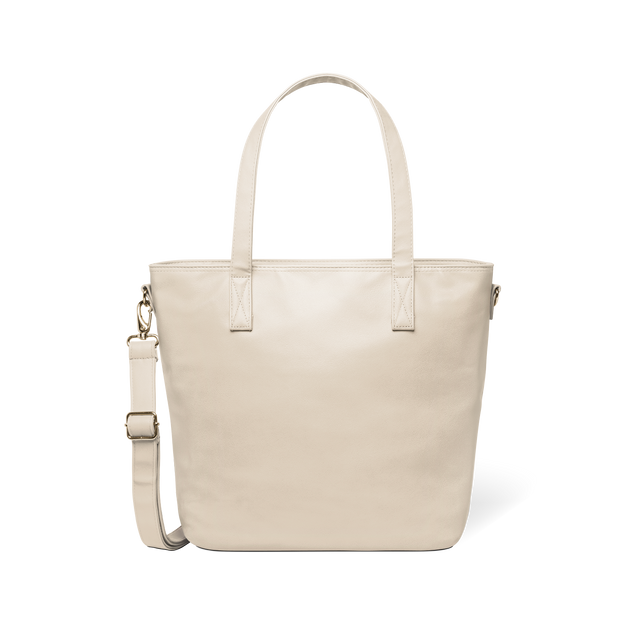 Oatmeal-colored tote bag with gold-toned metal hardware and handles against a white background