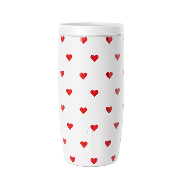 White insulated tumbler with secure lid featuring a repeating red heart grid pattern, centered on white background.