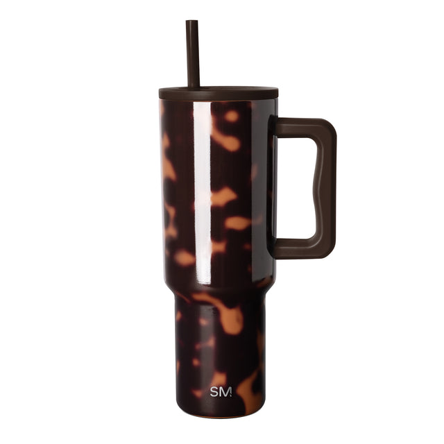Tortoiseshell pattern stainless steel tumbler with dark brown and amber tones, white vertical stripe, dark lid with integrated straw, squared handle, and Simple Modern logo on white background.
